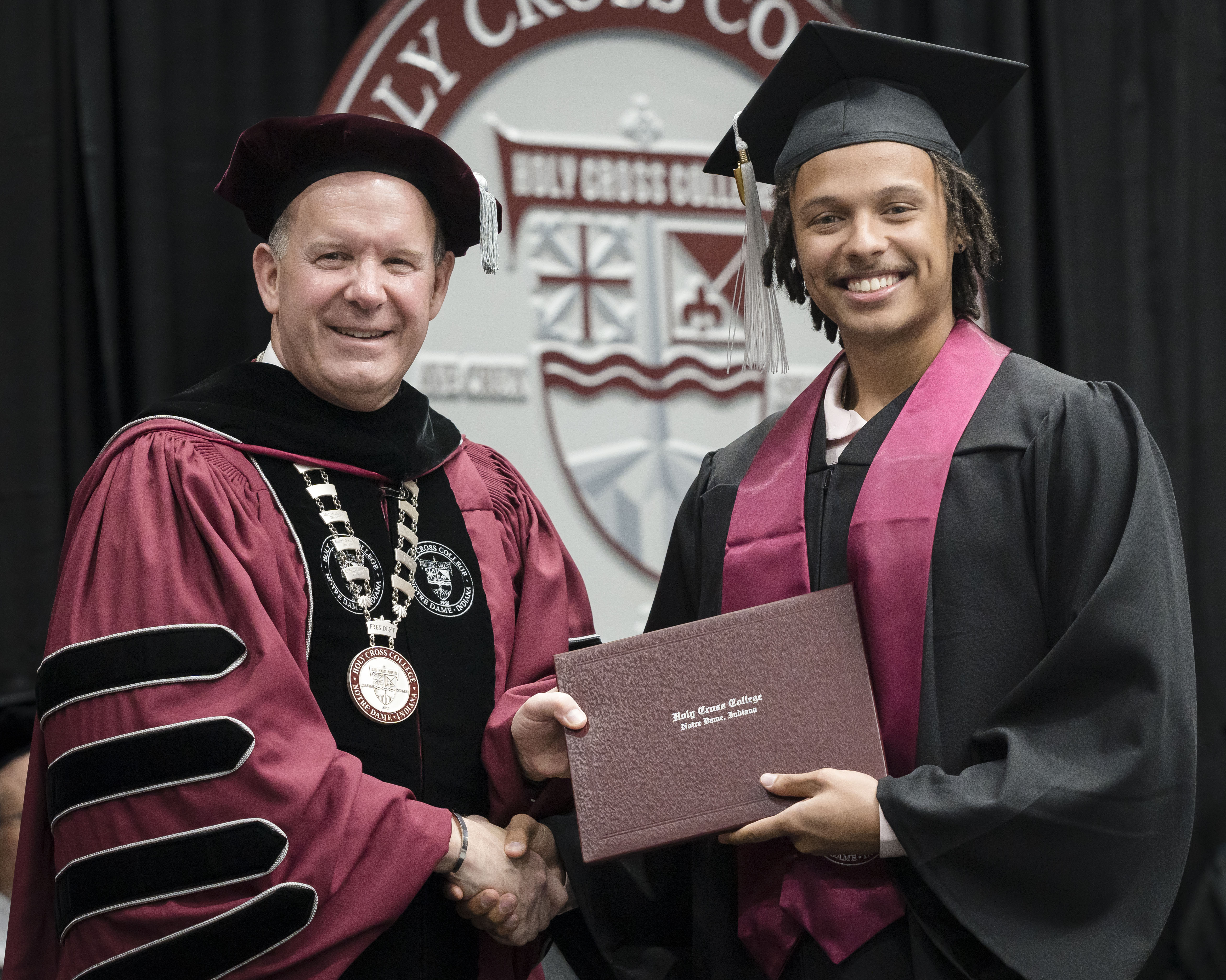 Isaiah at graduation holding a diploma